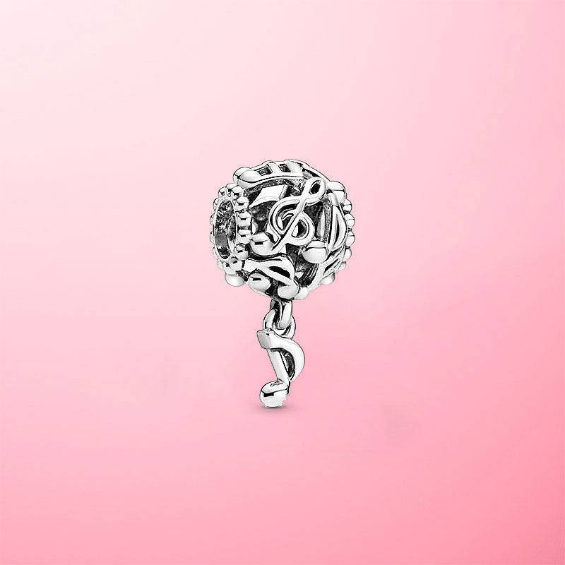 Sterling silver musical note charm with a dangling note accent, set against a soft pink background for an elegant jewelry showcase.