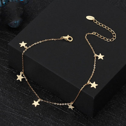 Gold anklet with star charms on black box