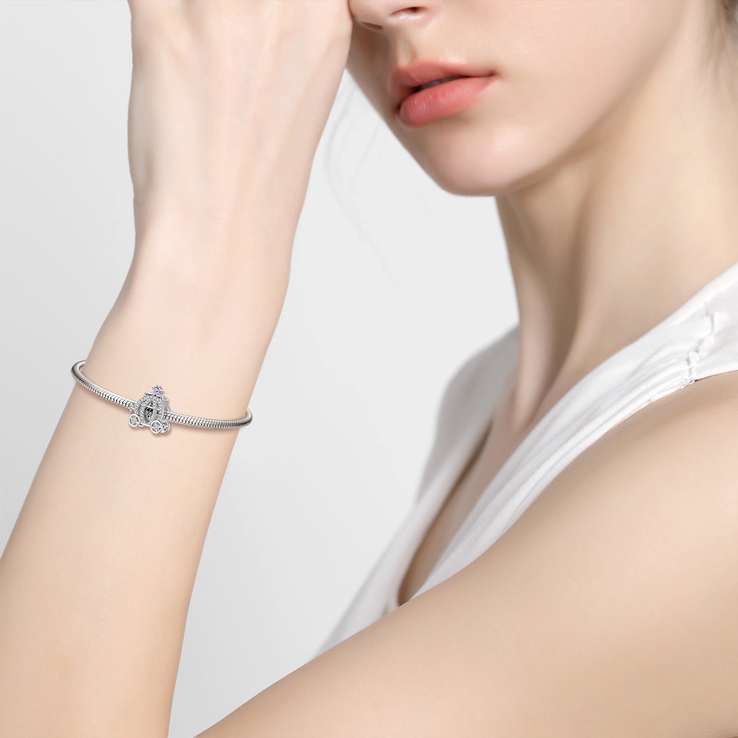 Woman wearing a bracelet with the Carriage Charm, highlighting its stylish and fairy tale-inspired design.