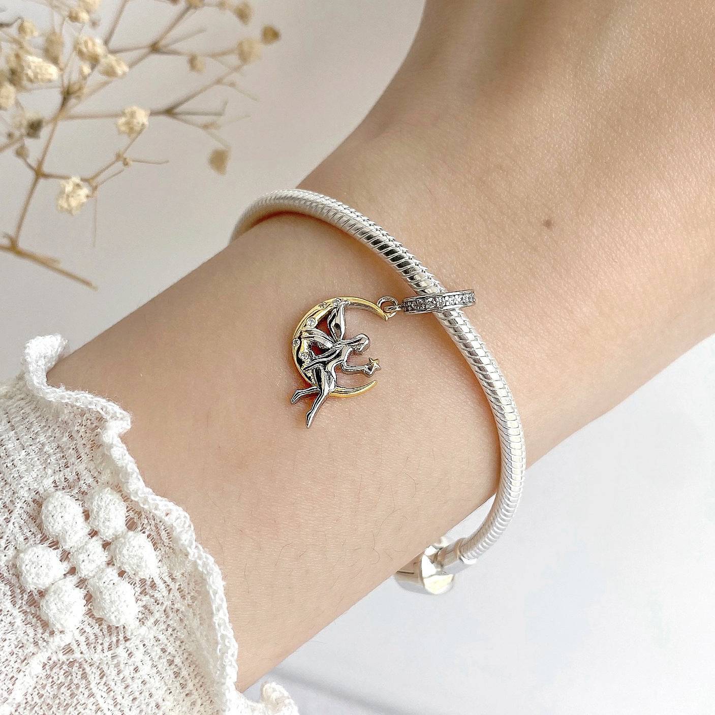 Elegant Moon Fairy Charm bracelet worn on a wrist, showcasing its intricate silver and gold design with a celestial fairy motif for a magical touch.