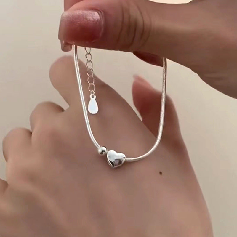 Close-up of the Heart Bead Silver Bracelet held in hand, highlighting the heart charm and adjustable clasp for a secure fit.